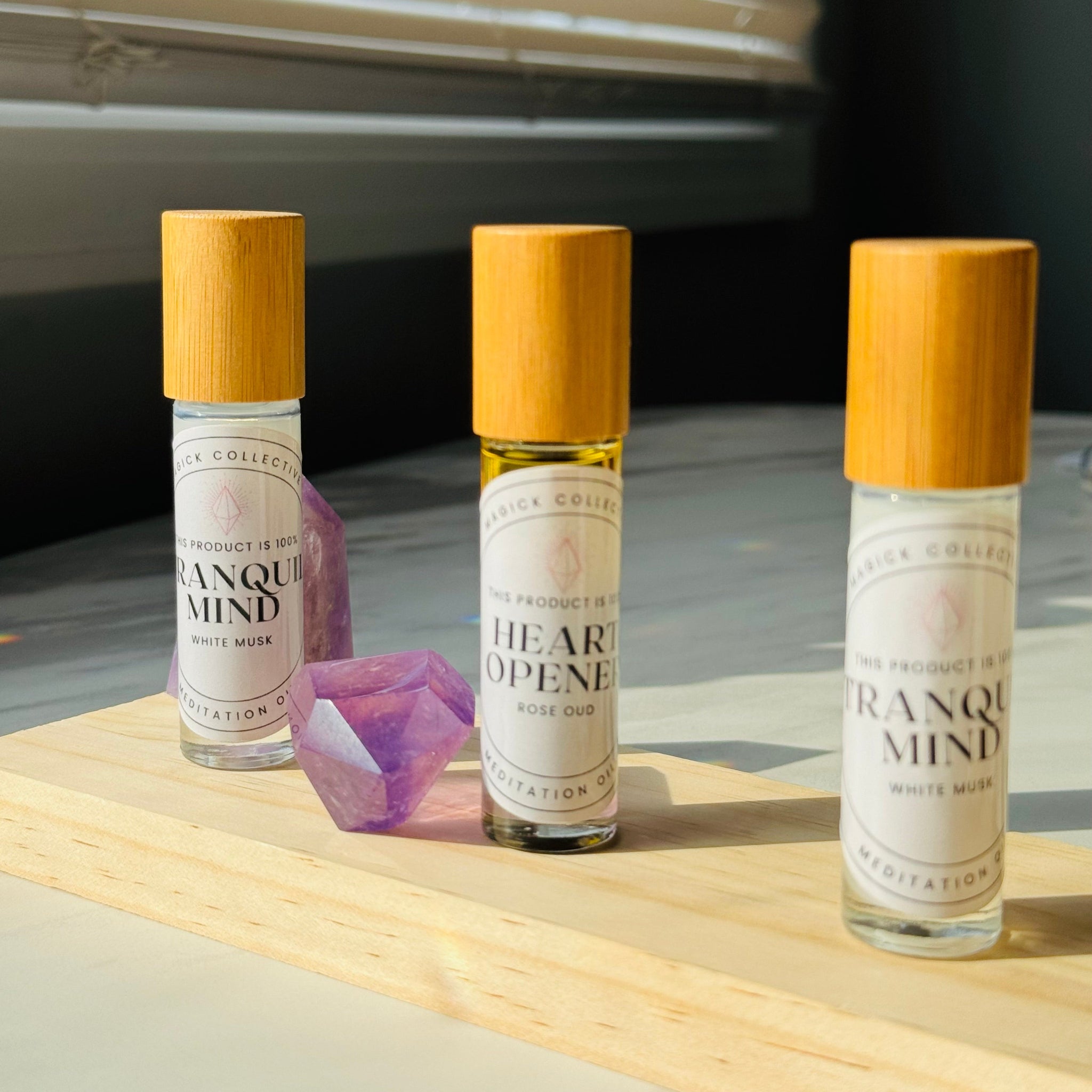 Heart Opener Oil and Tranquil Mind Oils on wooden surface with Amethyst