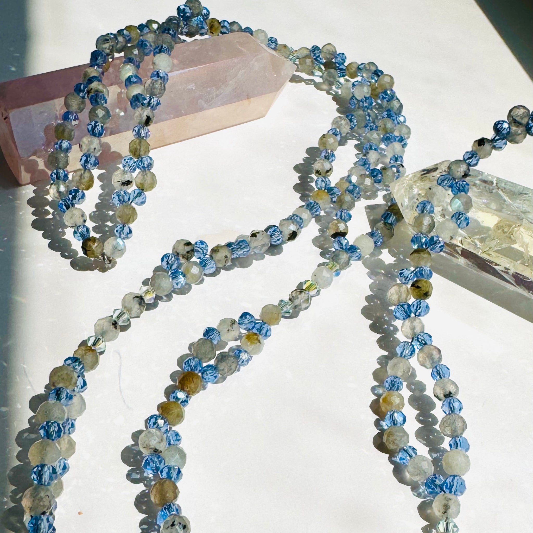 beaded moonstone tantric necklace on white surface and decorative crystals