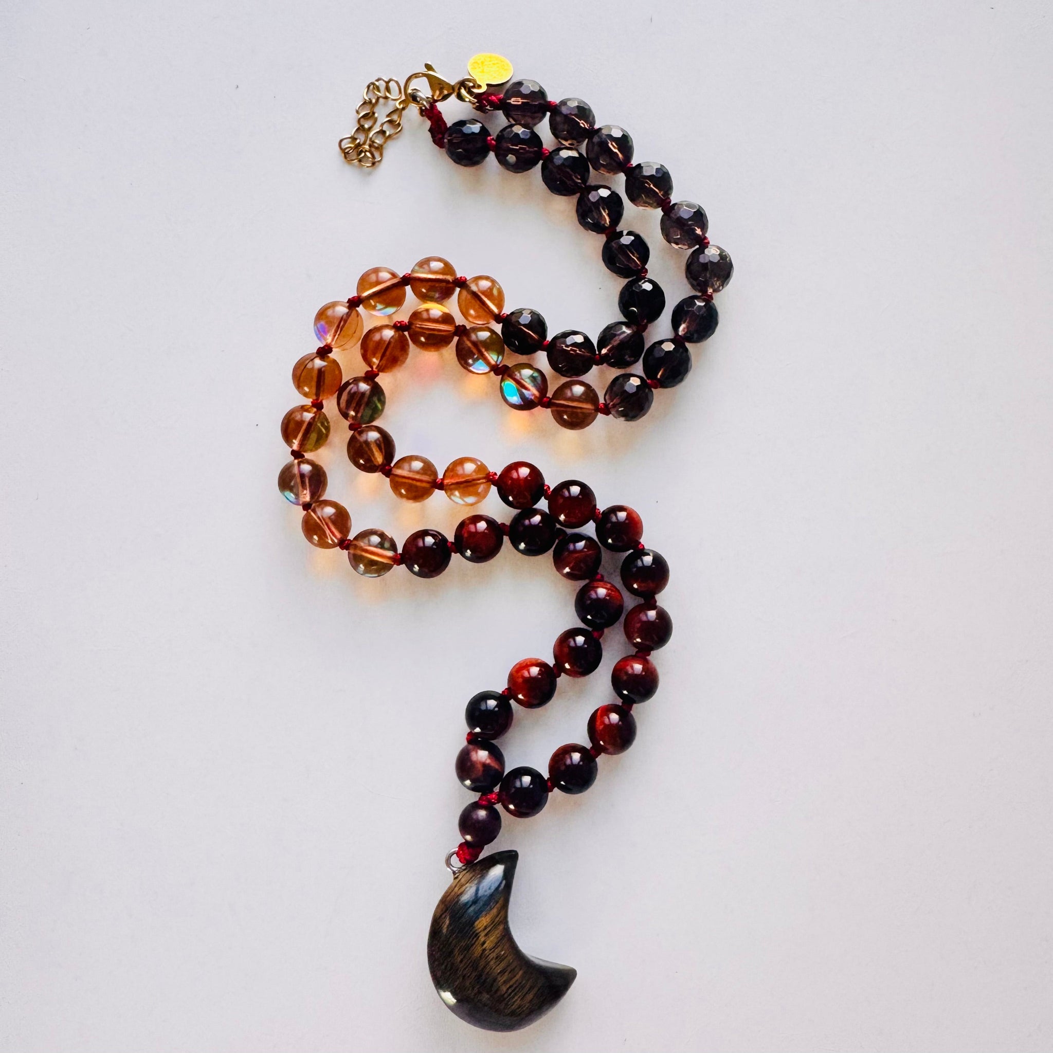 Beaded necklace with a crescent moon pendant on a light gray background