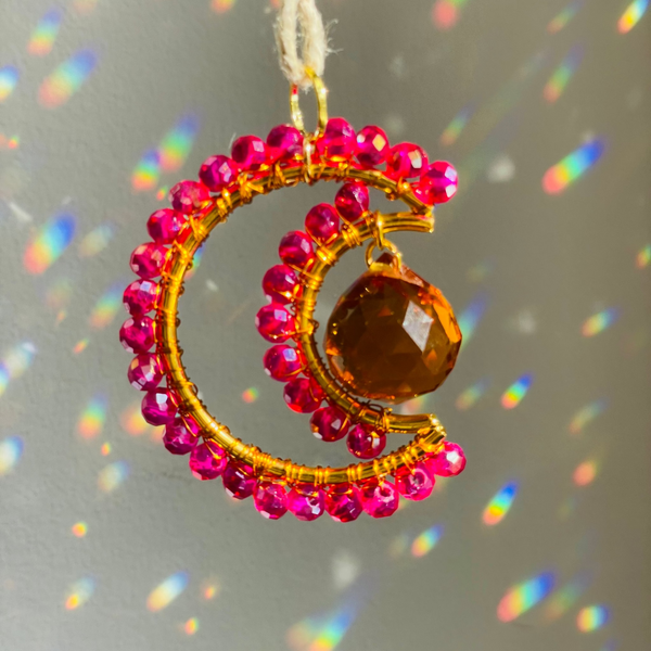 Magenta wire wrapped czech beads on to brass with orange prism creating rainbows on the wall