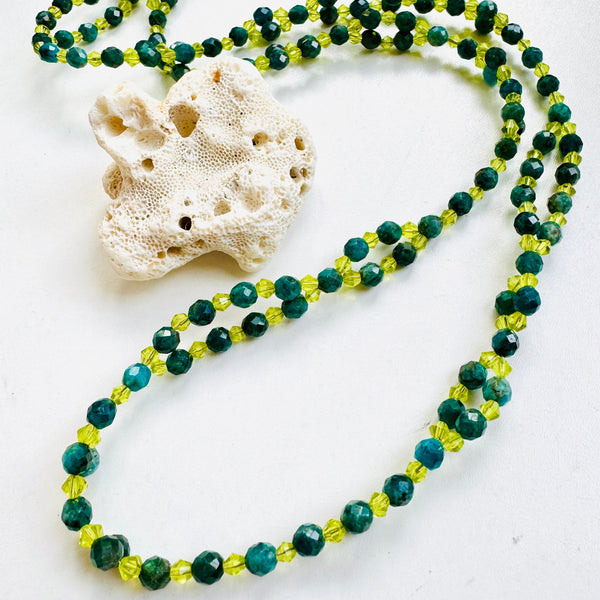 green beaded necklace with seashell on white background