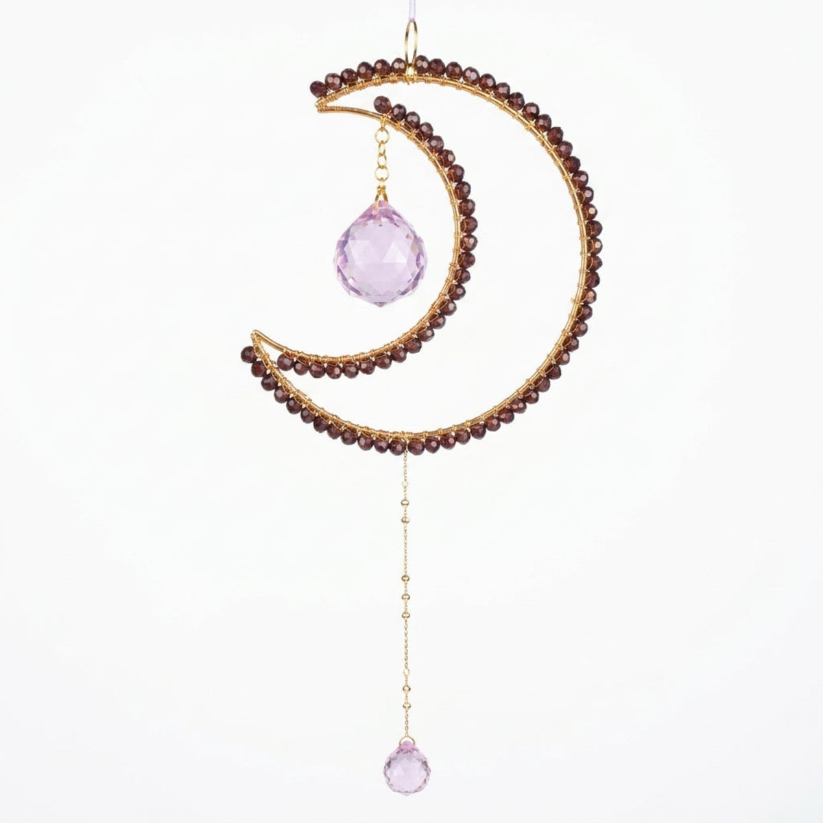 A crescent moon-shaped gold-toned beaded wall hanging ornament with two faceted light purple crystal drops, shown against a plain white background.
