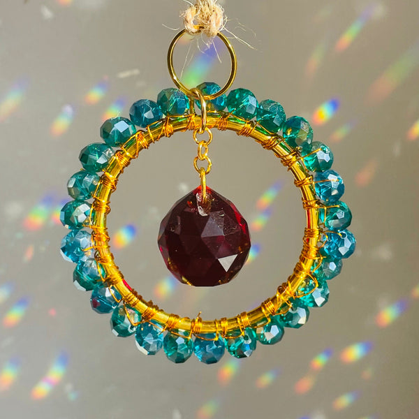 A mini circle suncatcher with a golden frame and clear crystal pendants hung from a chain.