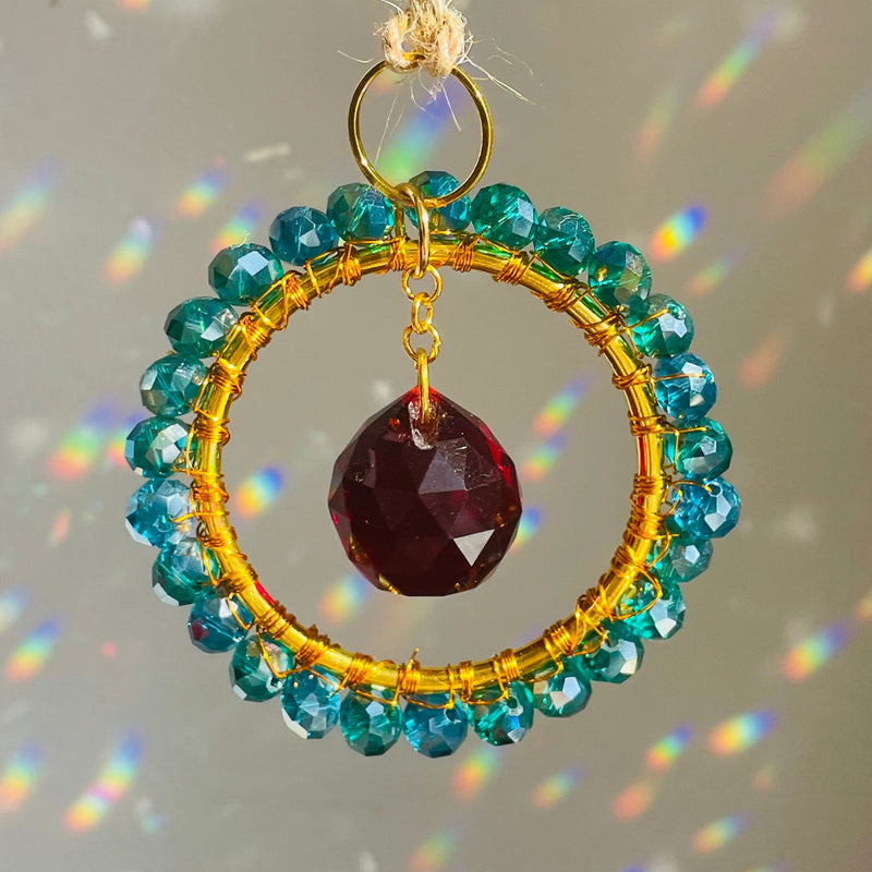 A mini circle suncatcher with a golden frame and clear crystal pendants hung from a chain.