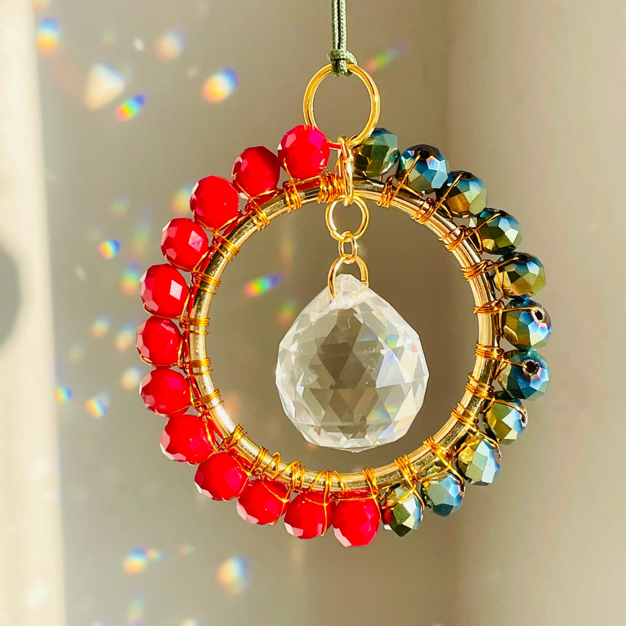 A mini circle suncatcher with a golden frame and clear crystal pendants hung from a chain.