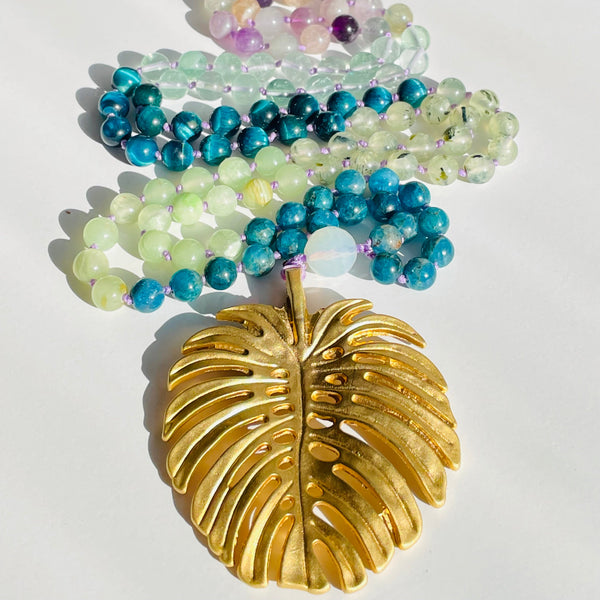 Set of beaded gemstones with a gold leaf charm on a white background