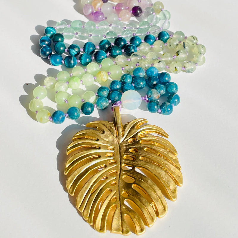 Set of beaded gemstones with a gold leaf charm on a white background