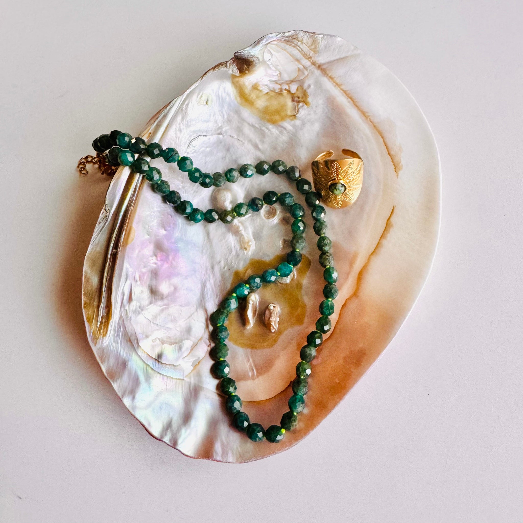 Green beaded necklace on a large shell with gold accents