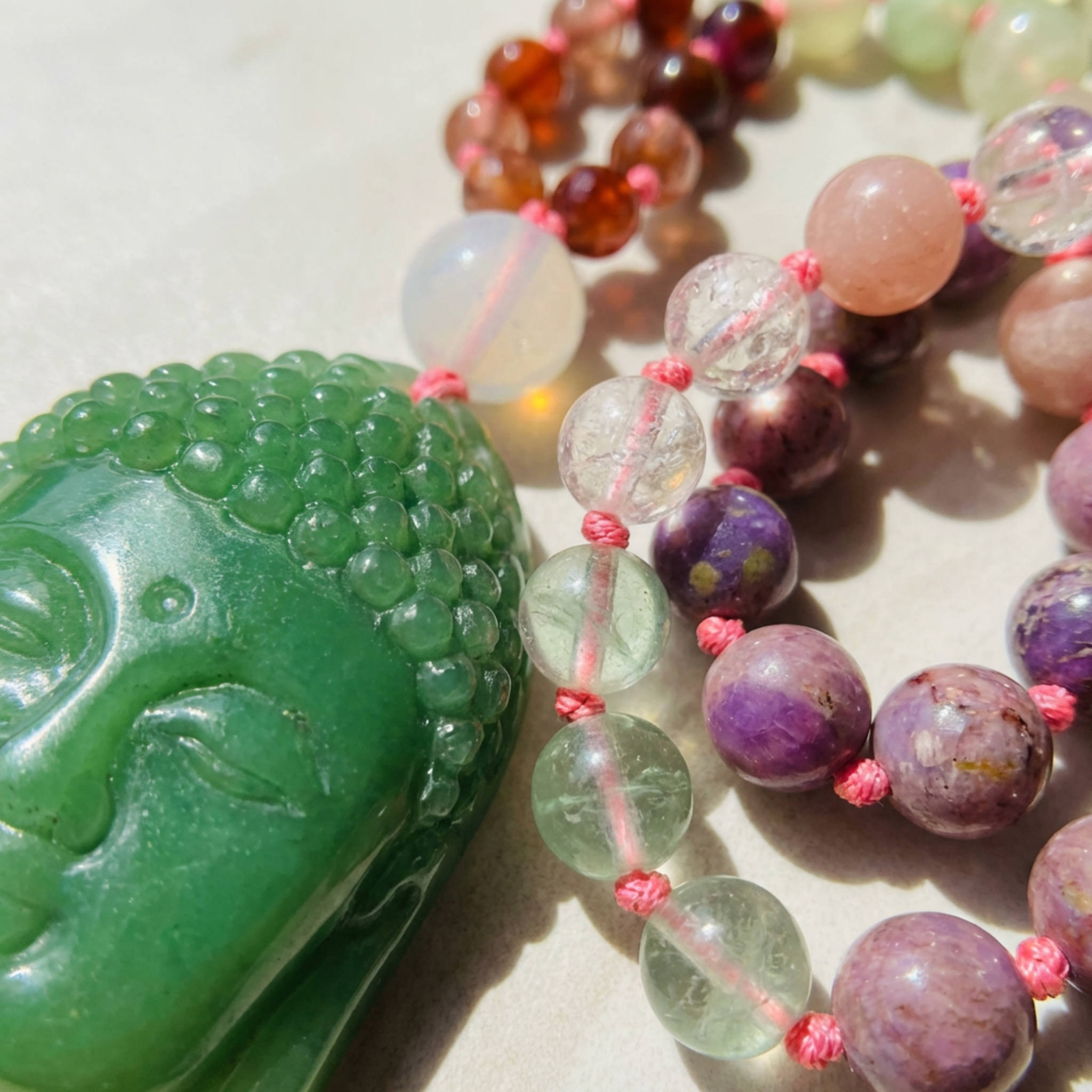 Colorful beaded necklace with a green Buddha pendant on a light background