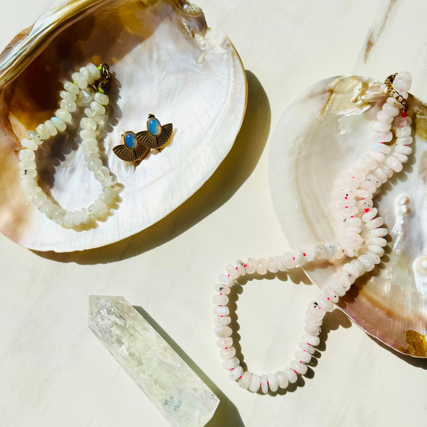 Two seashells with necklaces inside on a light background