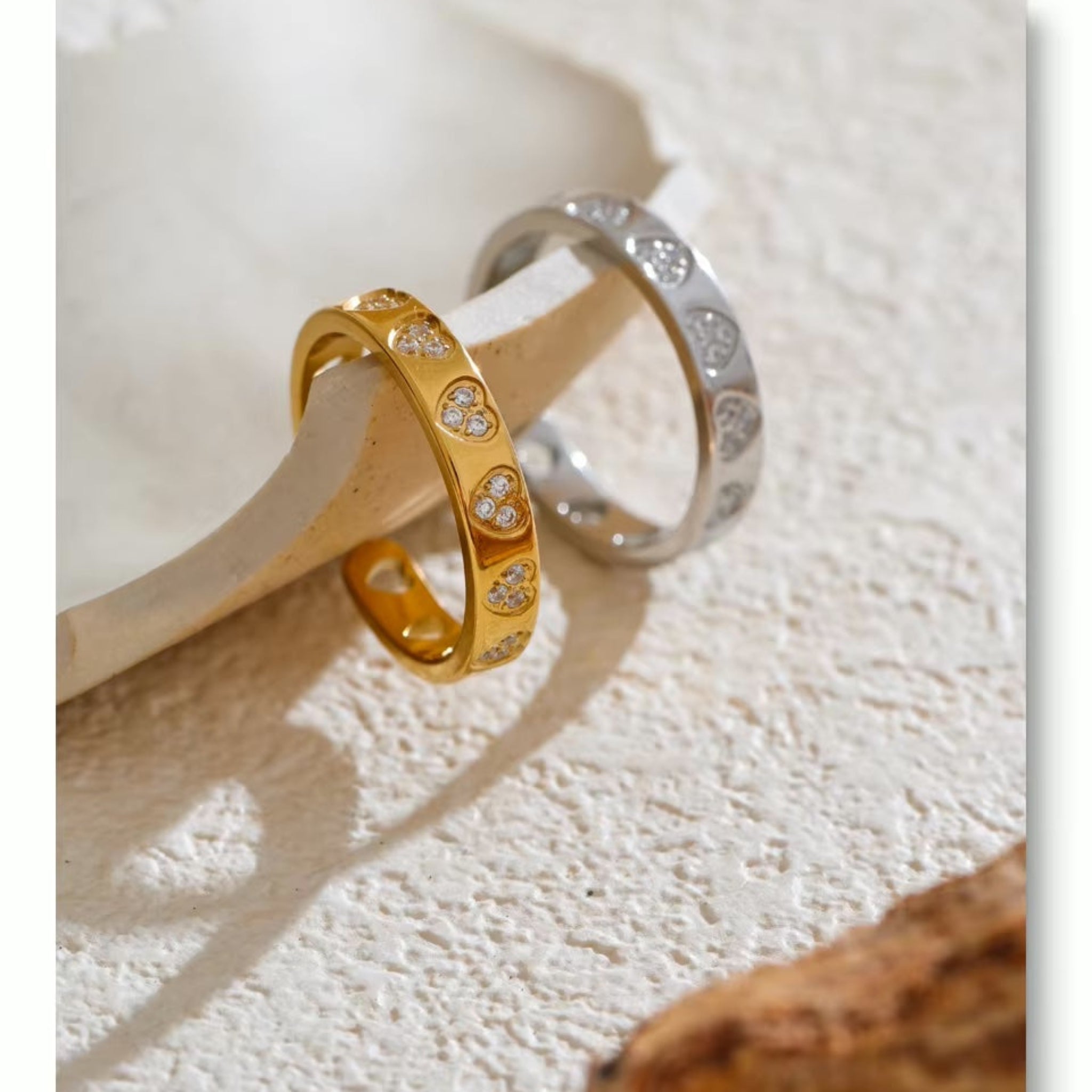 Two rings, one gold and one silver, on a textured surface.