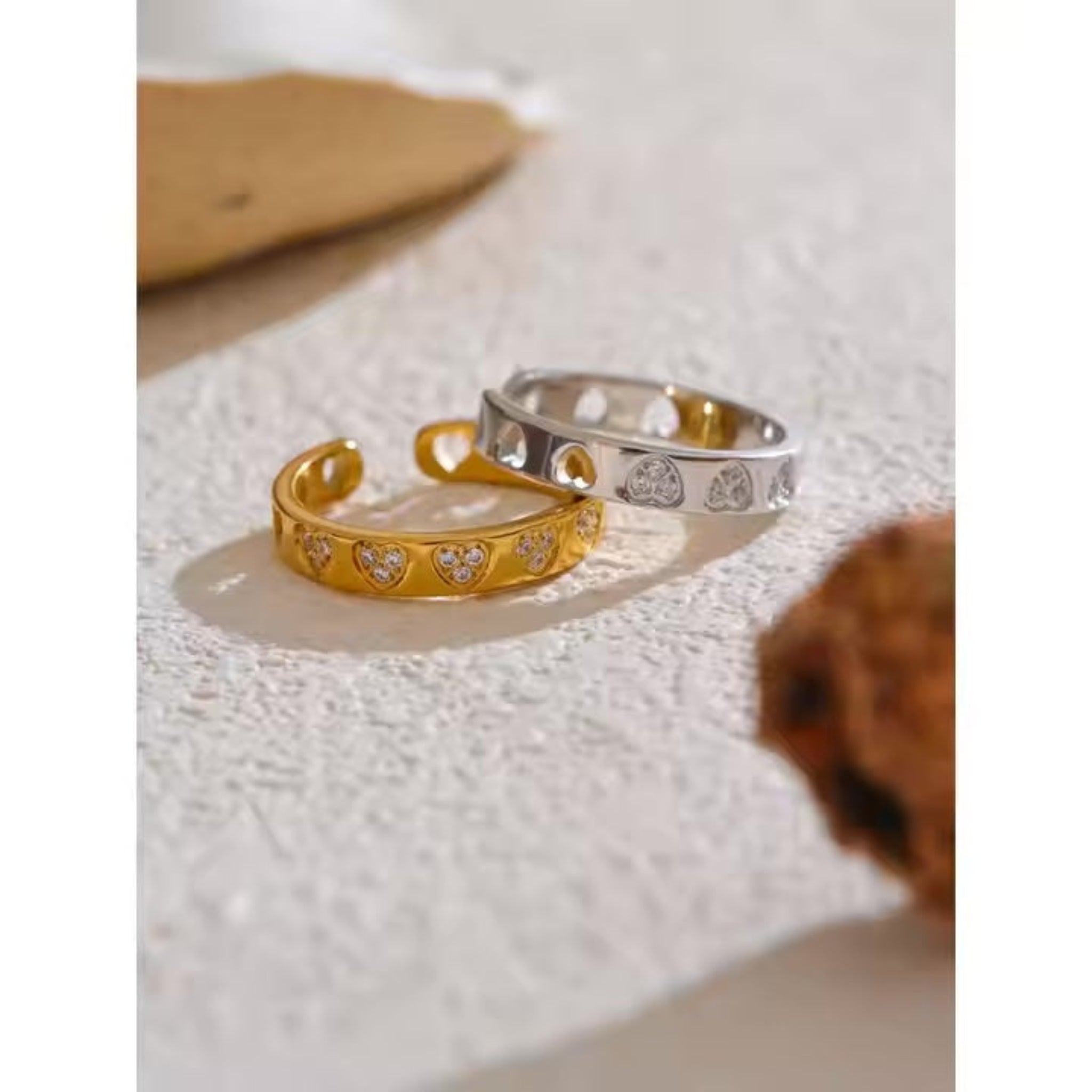 Two rings, one gold and one silver, on a textured surface.