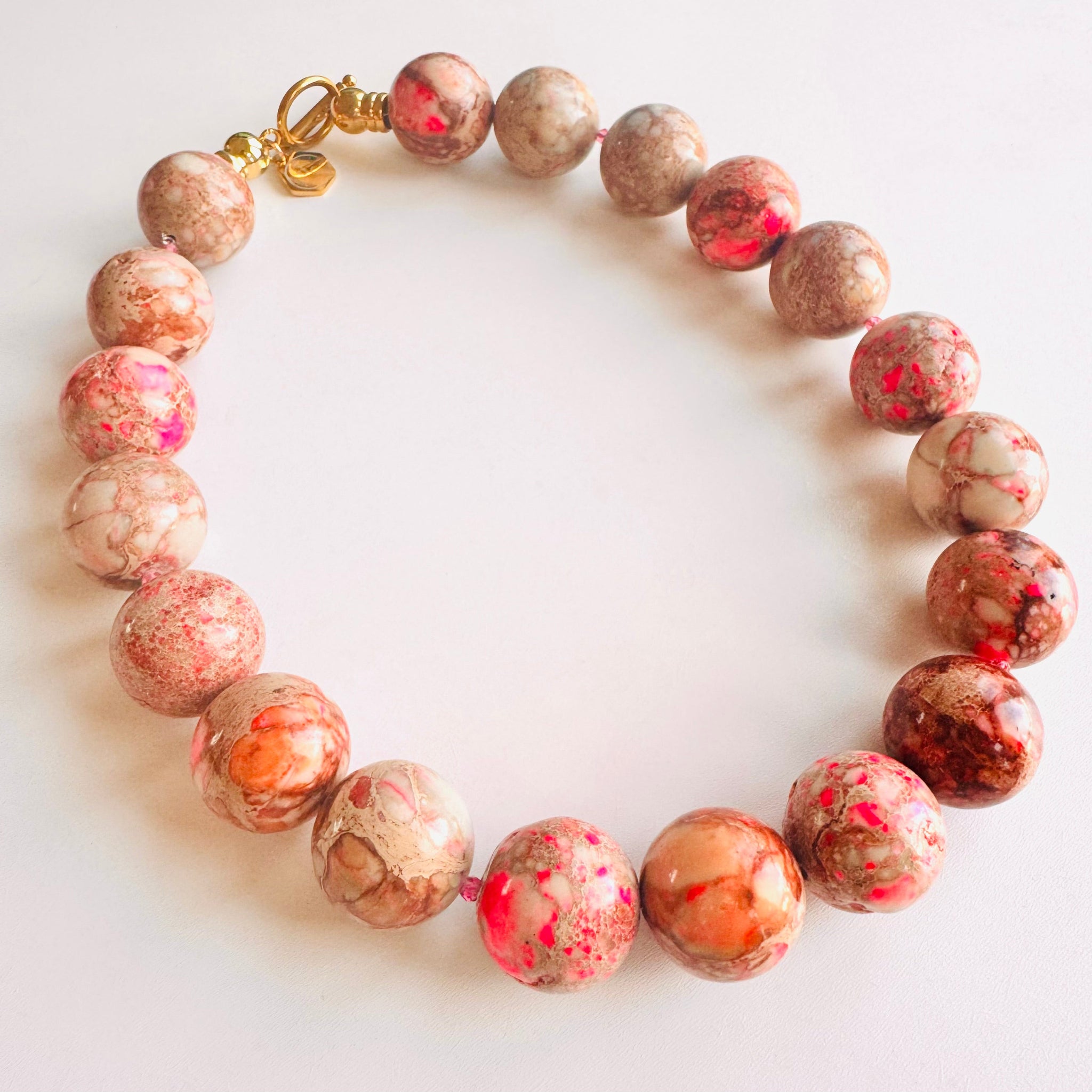 Marbled bead necklace with a gold clasp on a white background