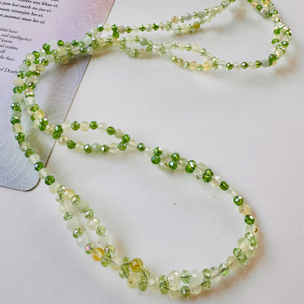Tantric necklace with green gemstones on white surface