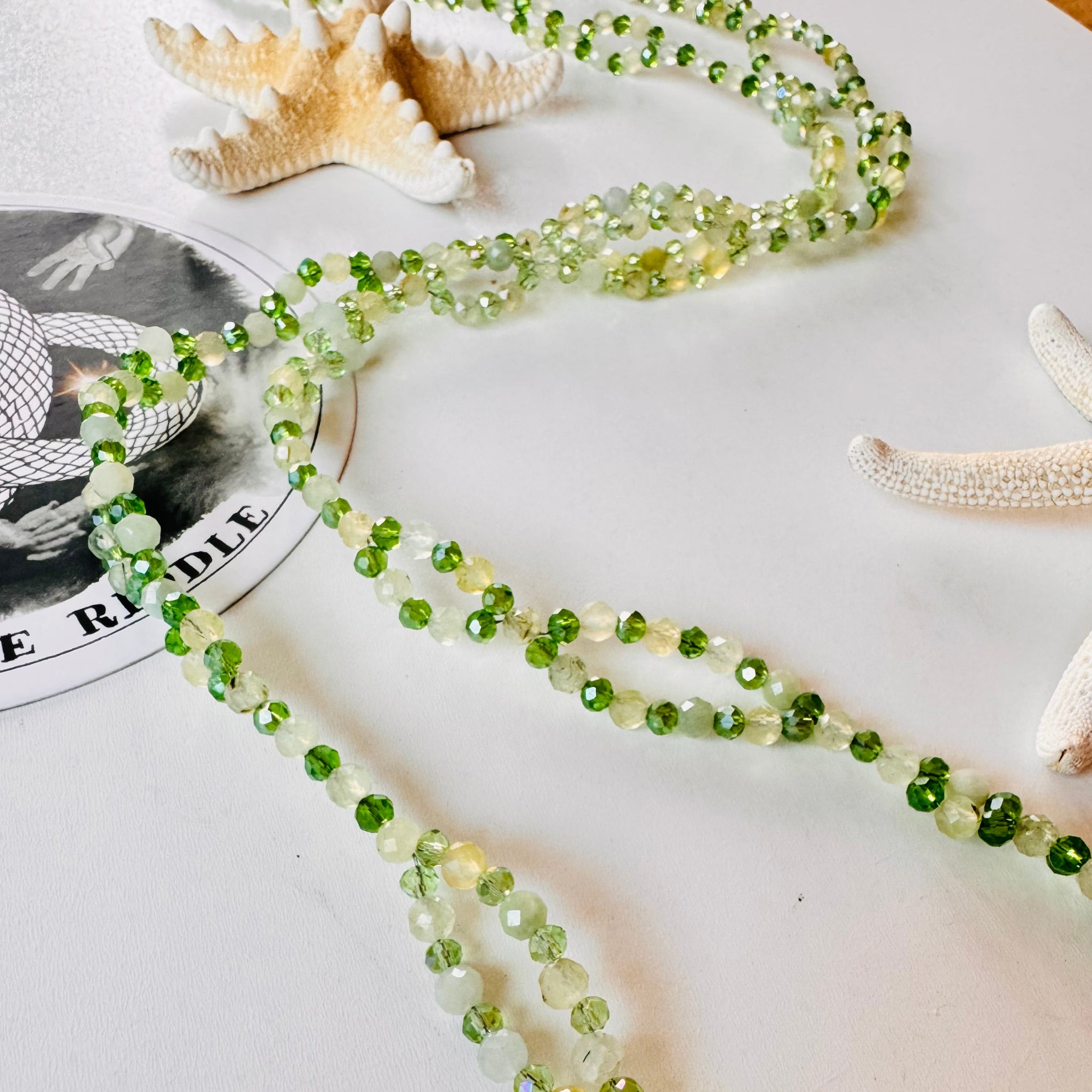 Tantric necklace made with green gemstones on white surface with decorative star