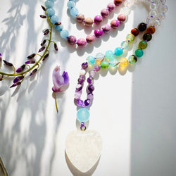 Closeup photo of beaded necklace with purple,blue and white beads with white crystal pendant