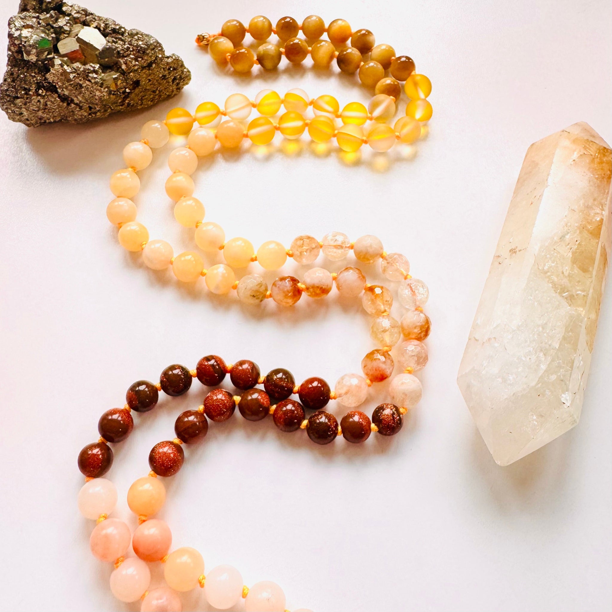 Necklace with beads and a pendant on a white surface with stones.