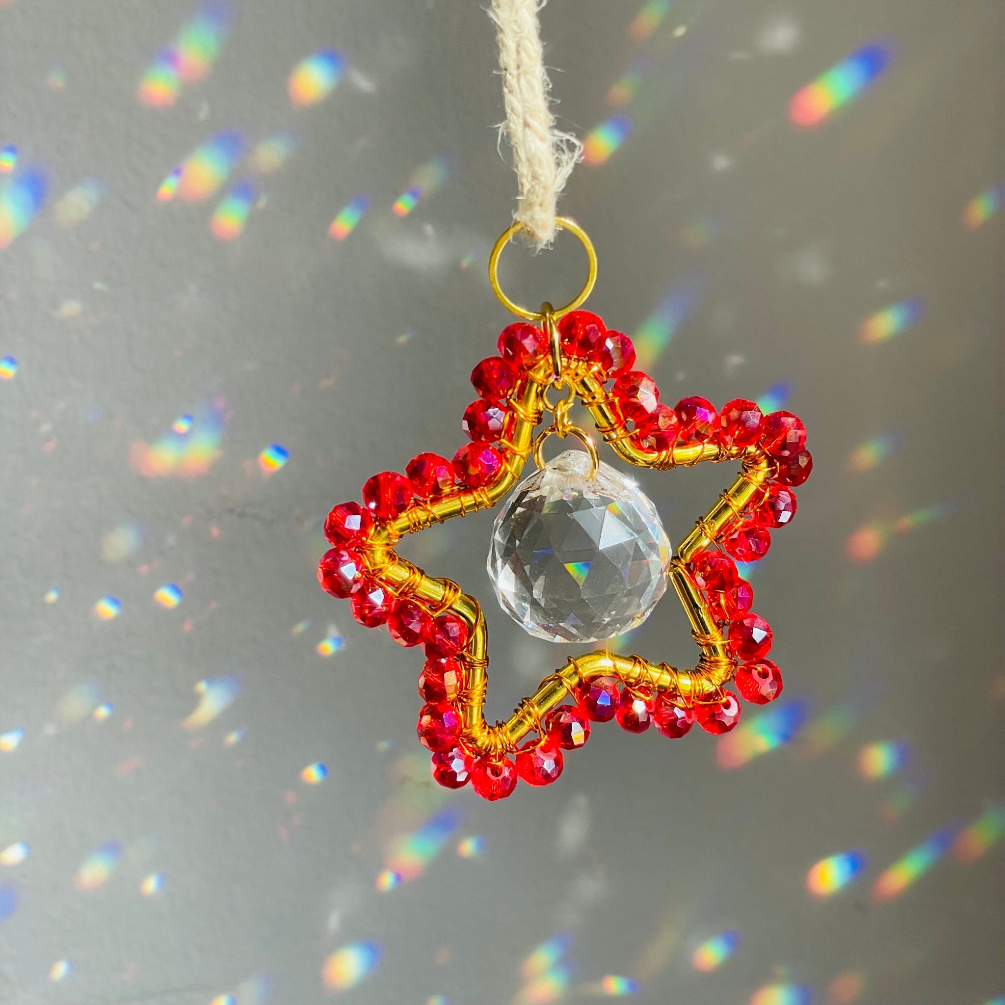 A mini star-shaped suncatcher with a central purple crystal and gold-tone metal frame, surrounded by clear crystals and a green chain for hanging.