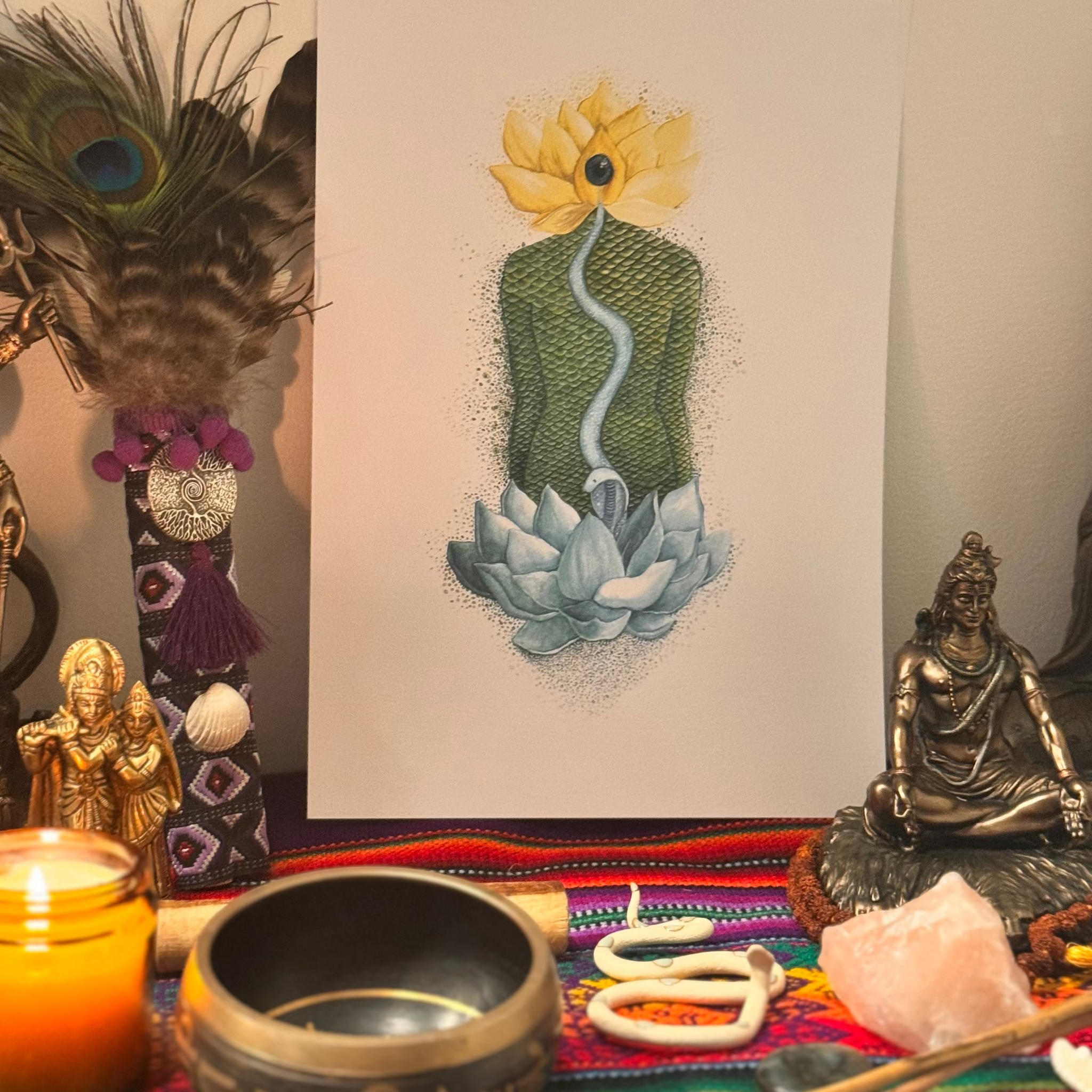 Decorative setup with peacock feathers, a painting of a flower and snake, and various objects on a colorful surface.