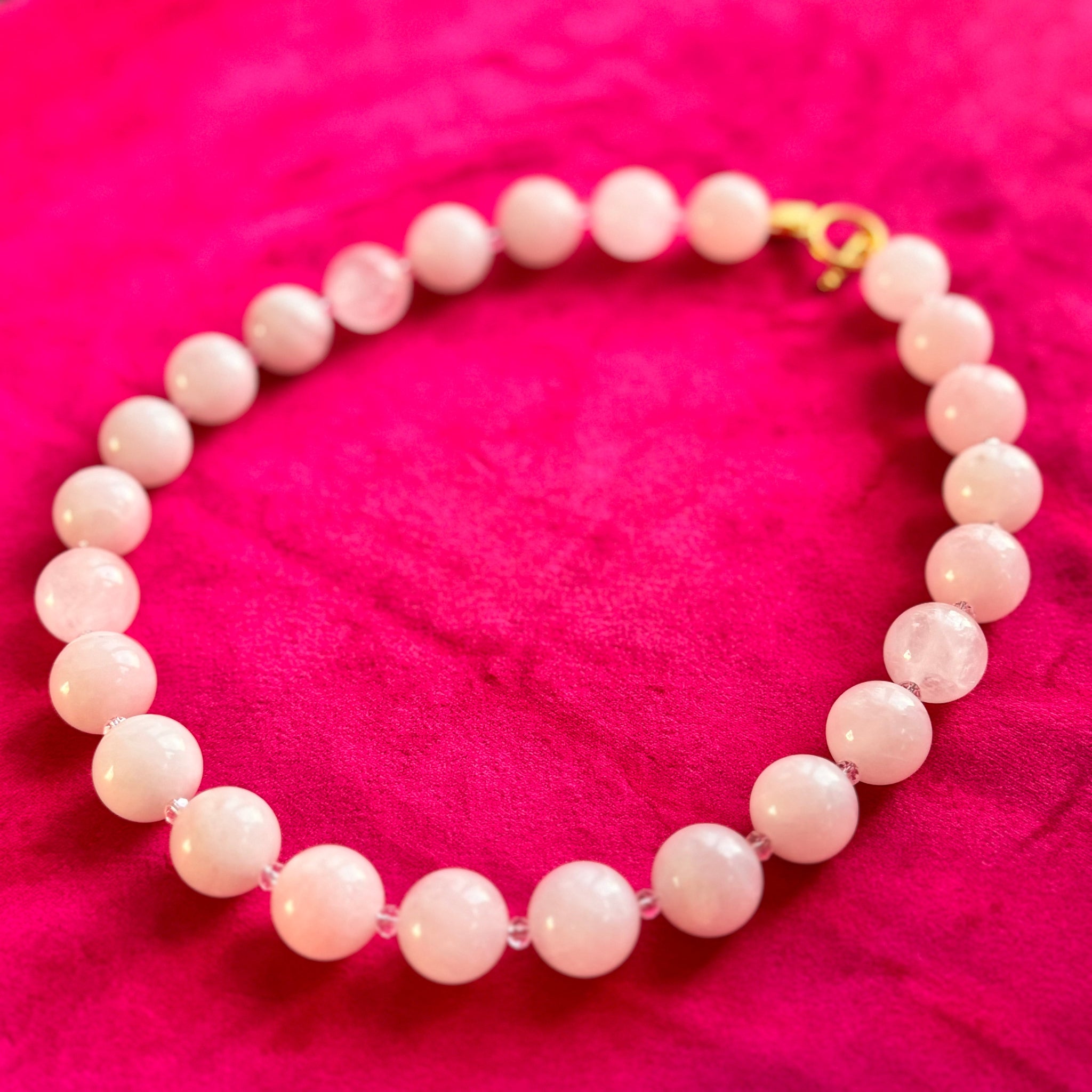 Pink beaded necklace on a pink fabric background