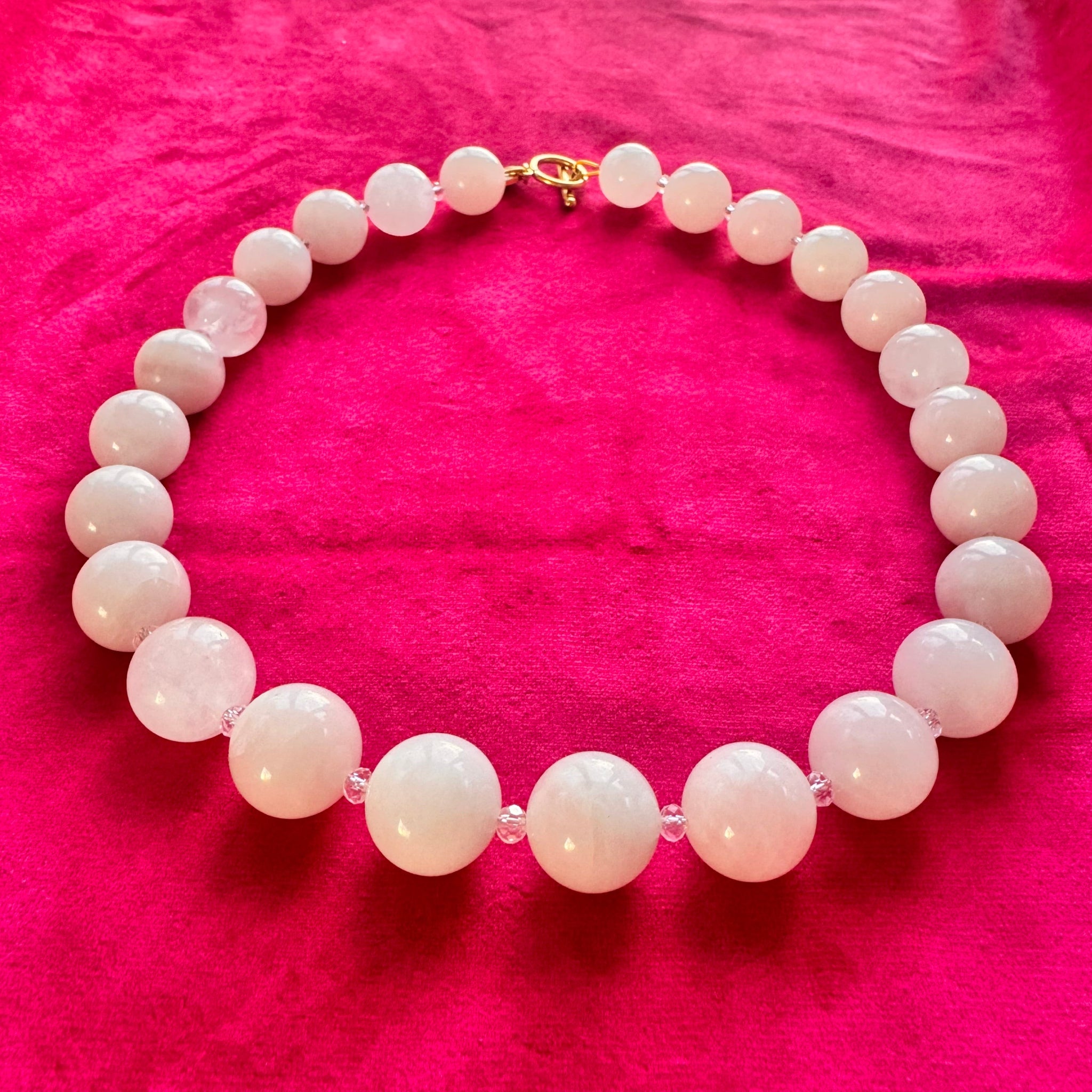 Necklace with pink beads on a pink fabric background