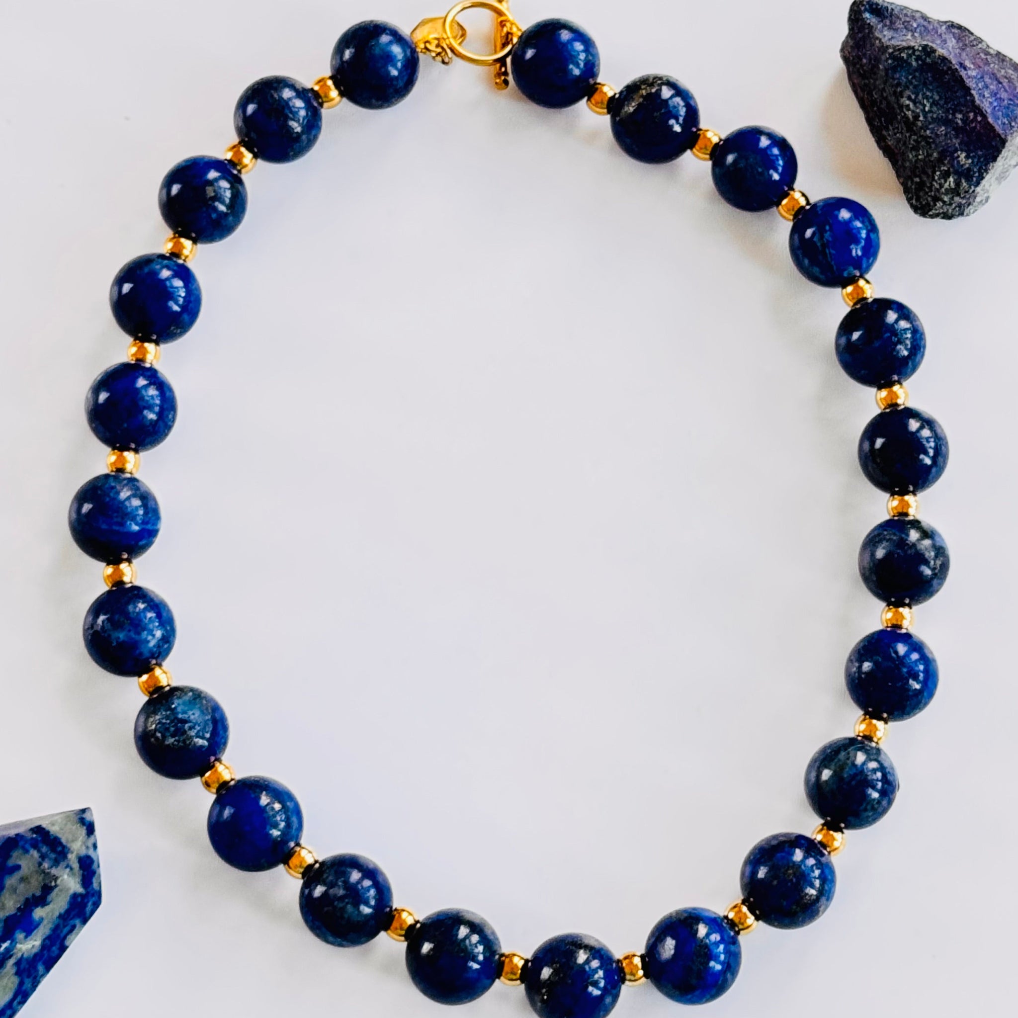 Blue beaded bracelet with gold accents on a white background