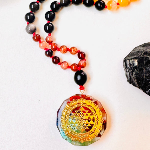 Colorful beaded necklace with a Sri Yantra pendant on a white background