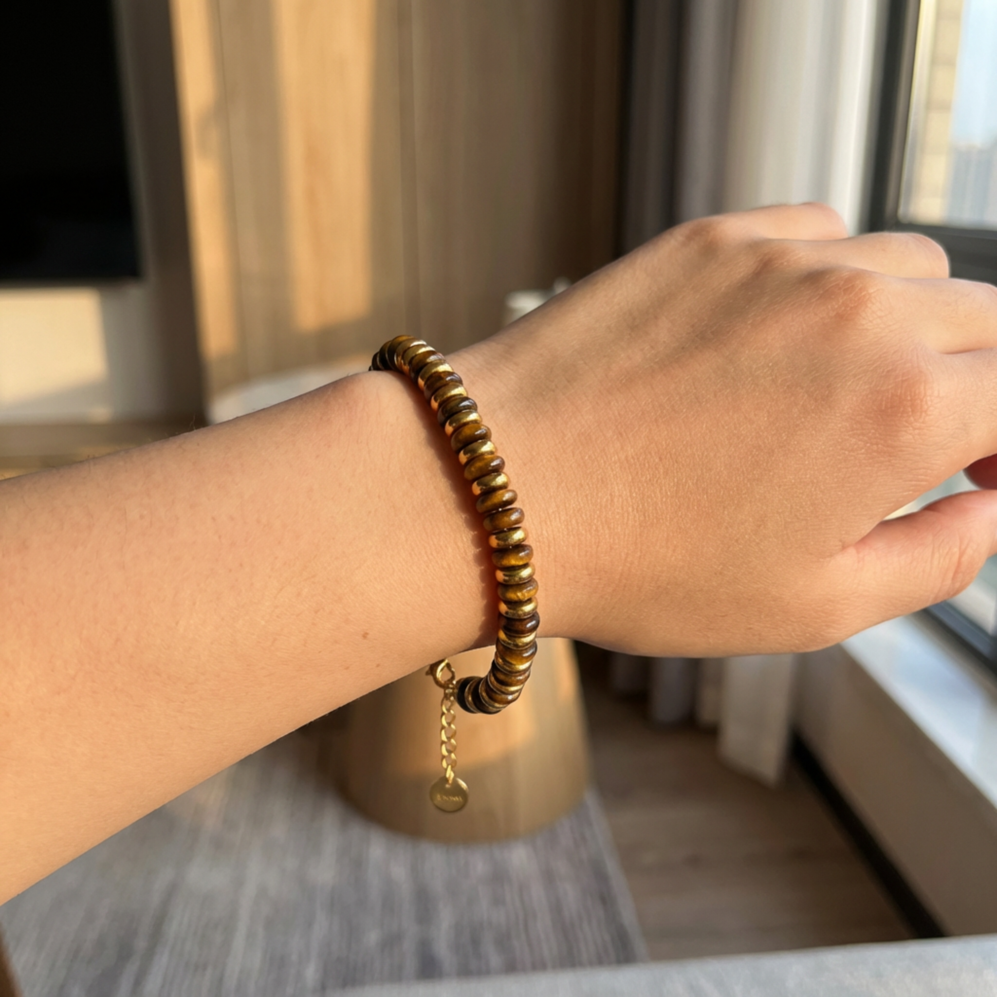 Hand wearing a beaded bracelet with a blurred indoor background