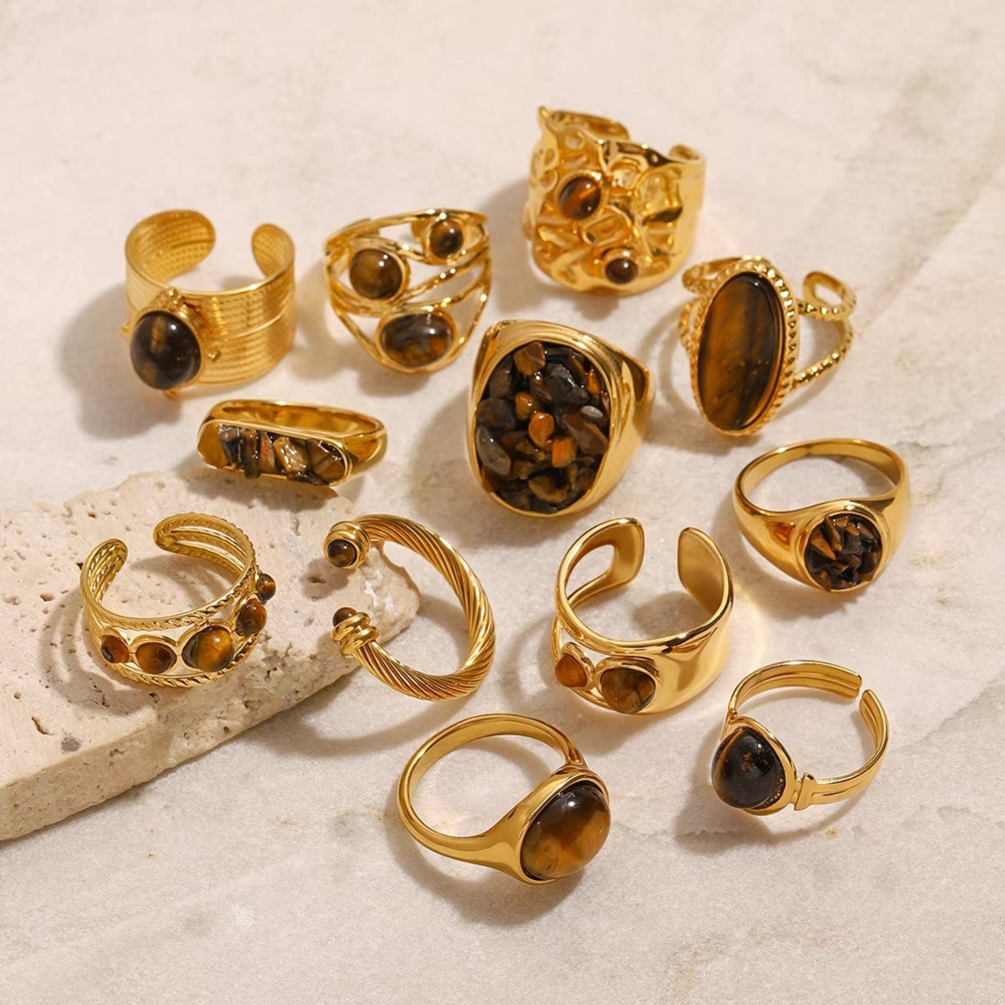 Collection of gold rings with embedded stones on a textured surface