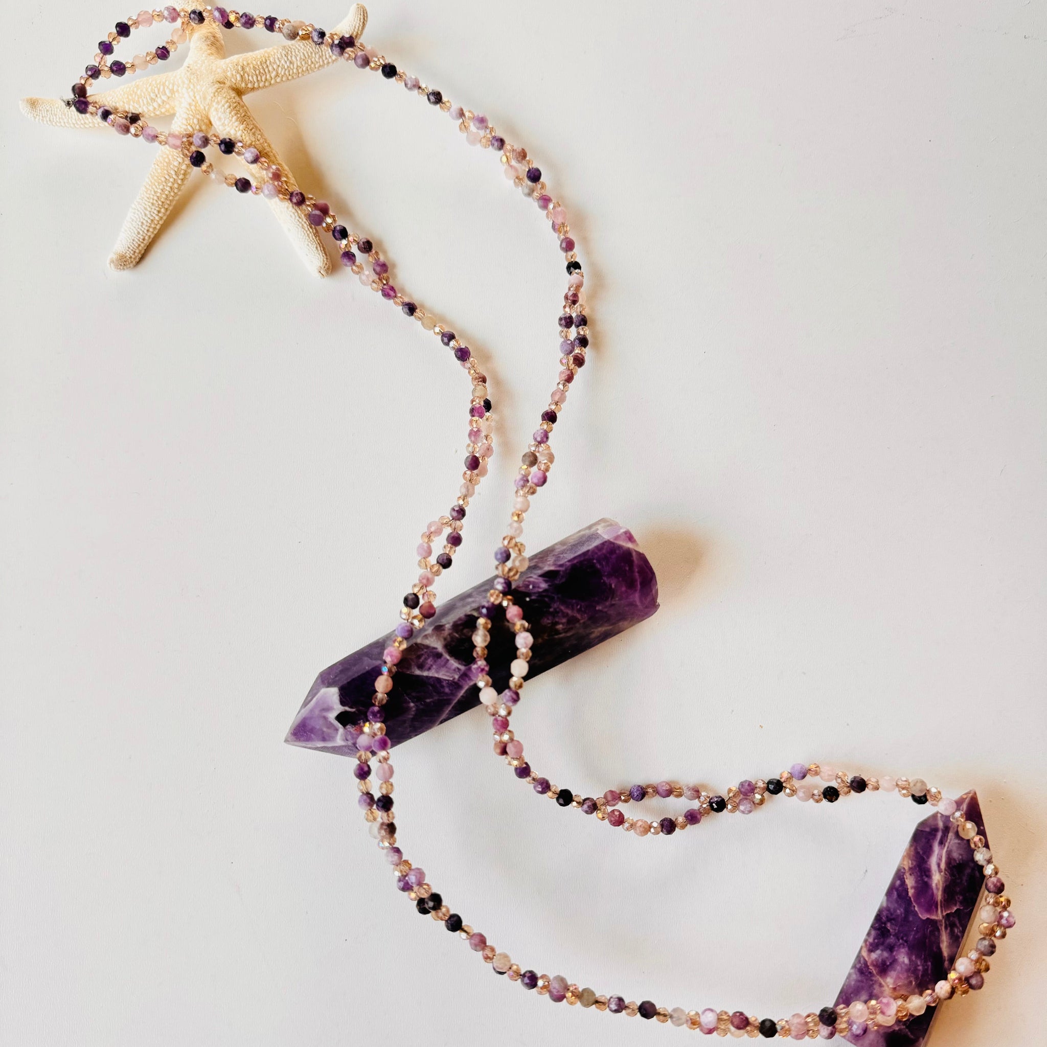 Lepidolite Tantric Necklace on white surface with star and purple crystal as decoration

