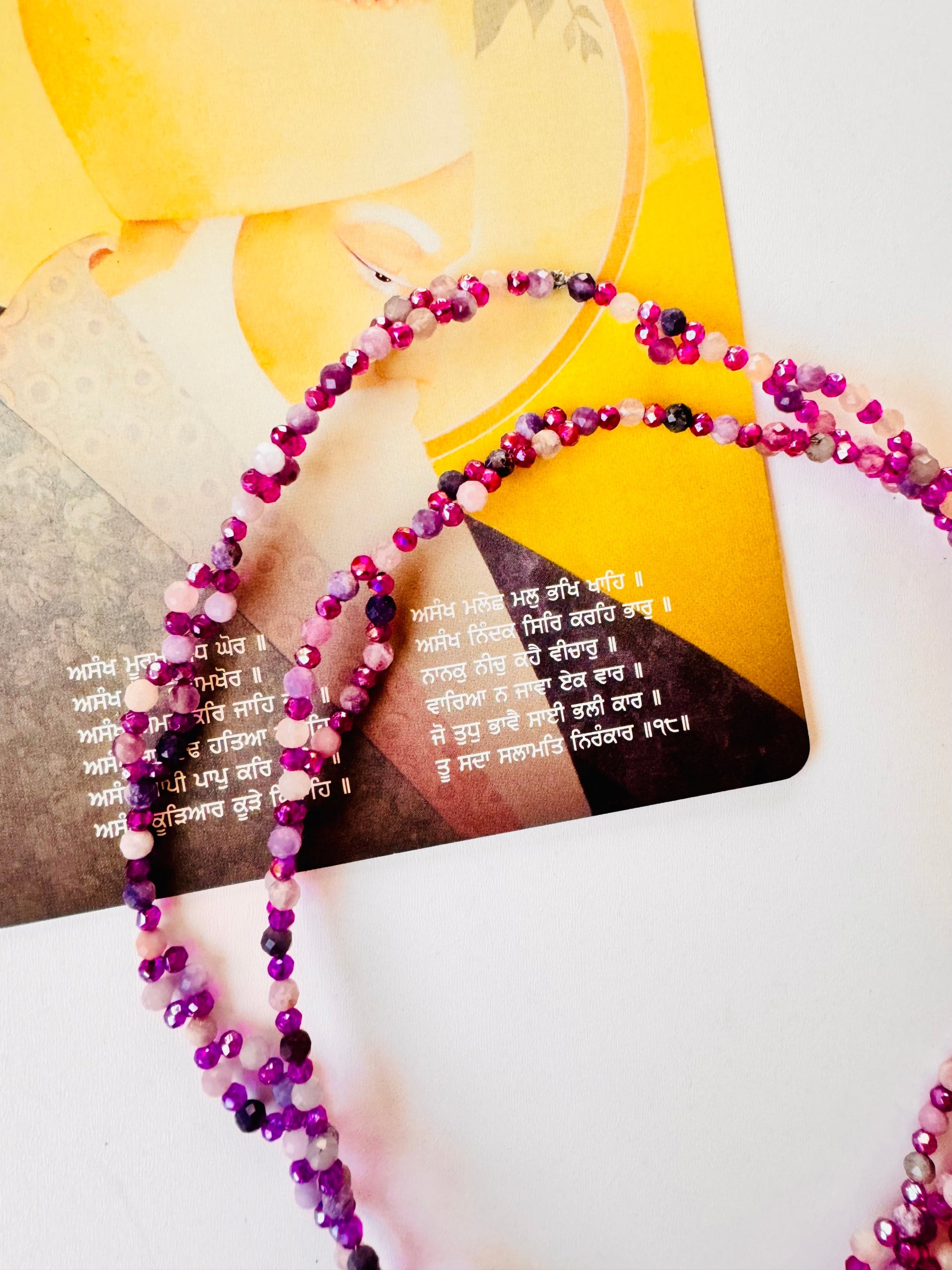 Lepidolite Tantric Necklace with a mantra card on white surface
