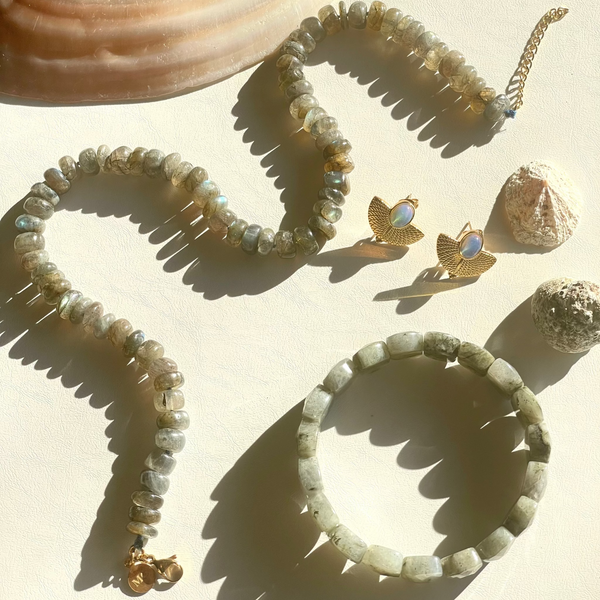 Beaded bracelet and earrings with a shell on a light background