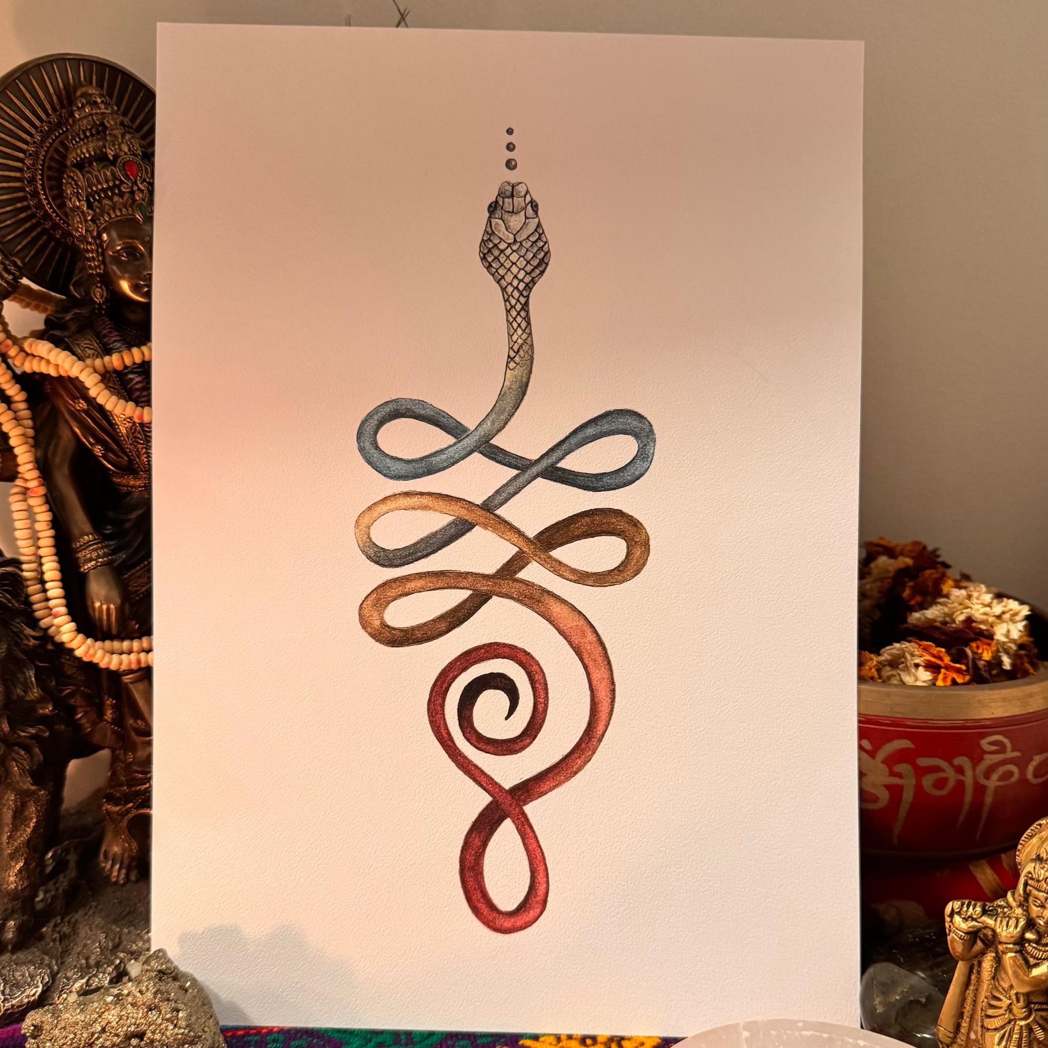 Decorative artwork of intertwined snakes on a white background, surrounded by decorative items.