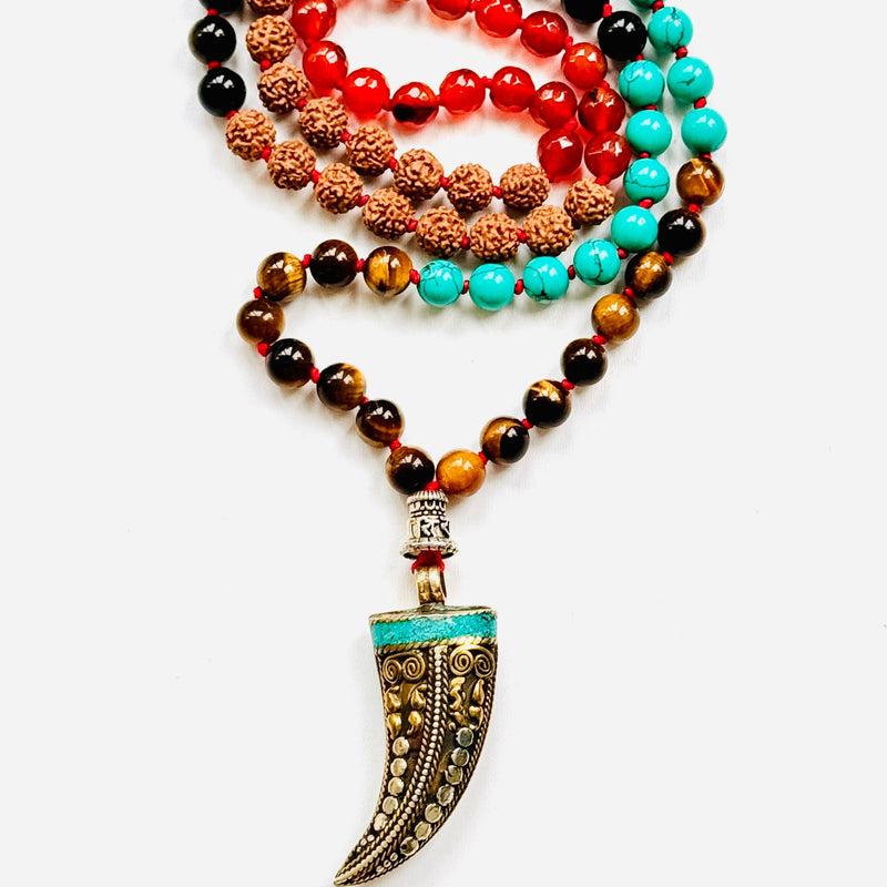 A variety of colorful gemstone beads and a Tibetan horn pendant, arranged on a white background.