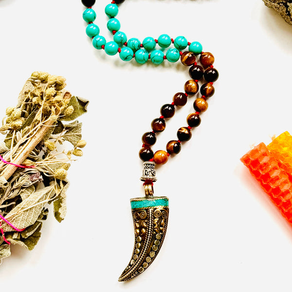 A variety of colorful gemstone beads and a Tibetan horn pendant, arranged on a white background closeup image.