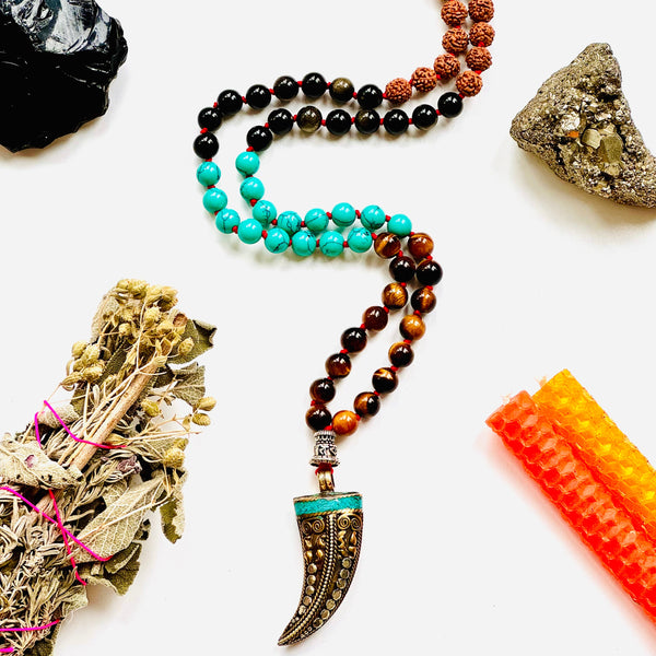 A variety of colorful gemstone beads and a Tibetan horn pendant, arranged on a white background.