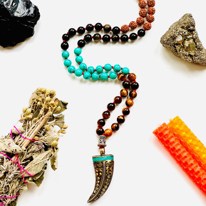 A variety of colorful gemstone beads and a Tibetan horn pendant, arranged on a white background.
