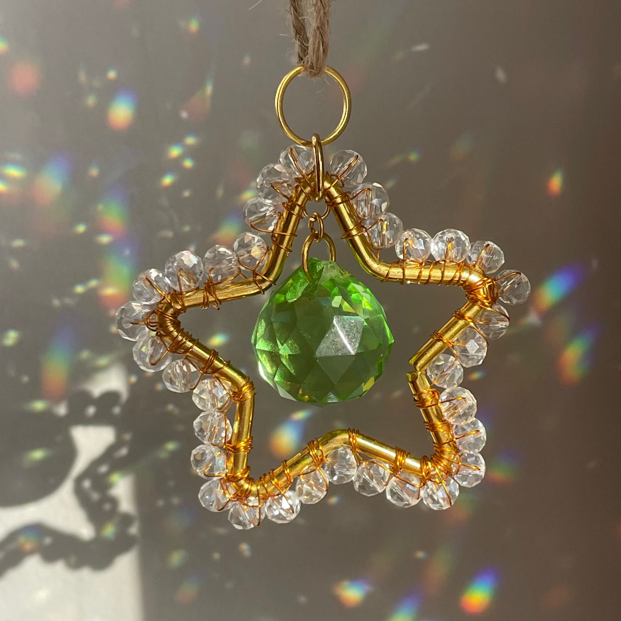 Star-shaped pendant with gold beads and a green gemstone on a dark background