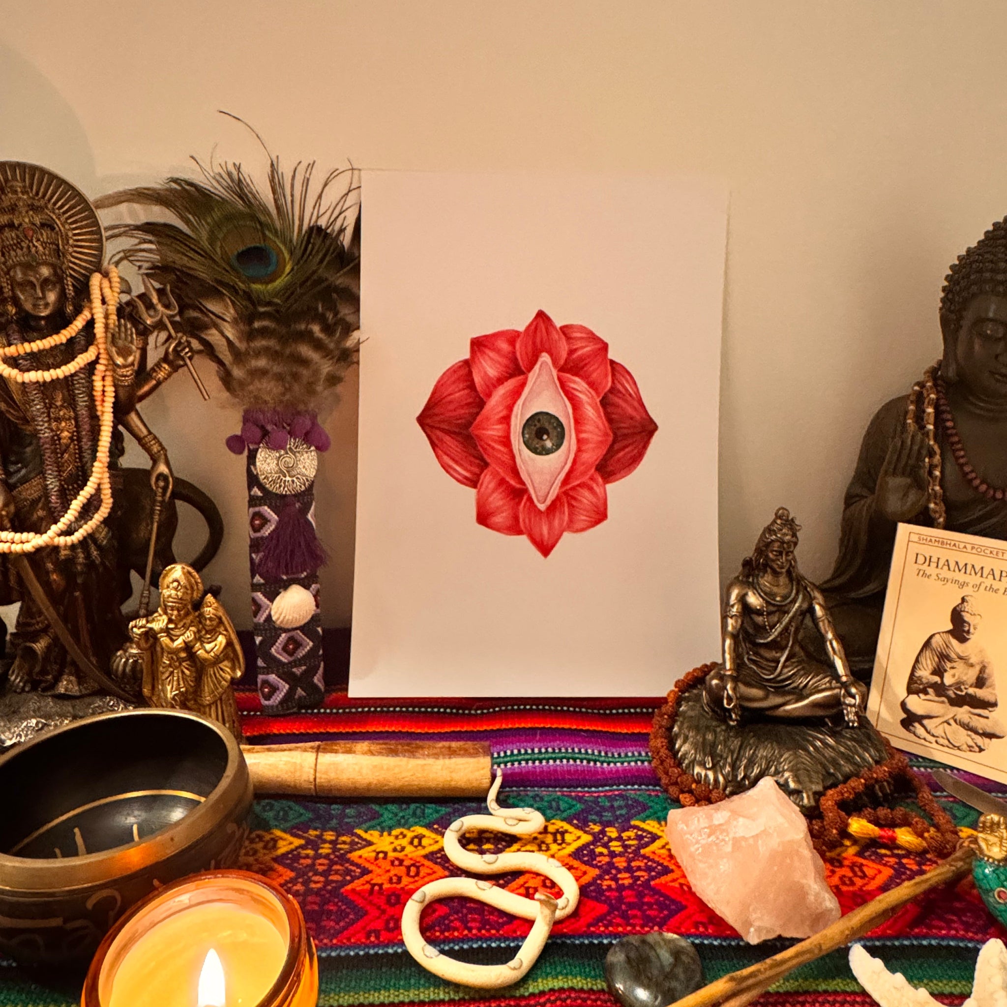 Mystical arrangement with a red flower drawing, candles, and decorative items on a table.