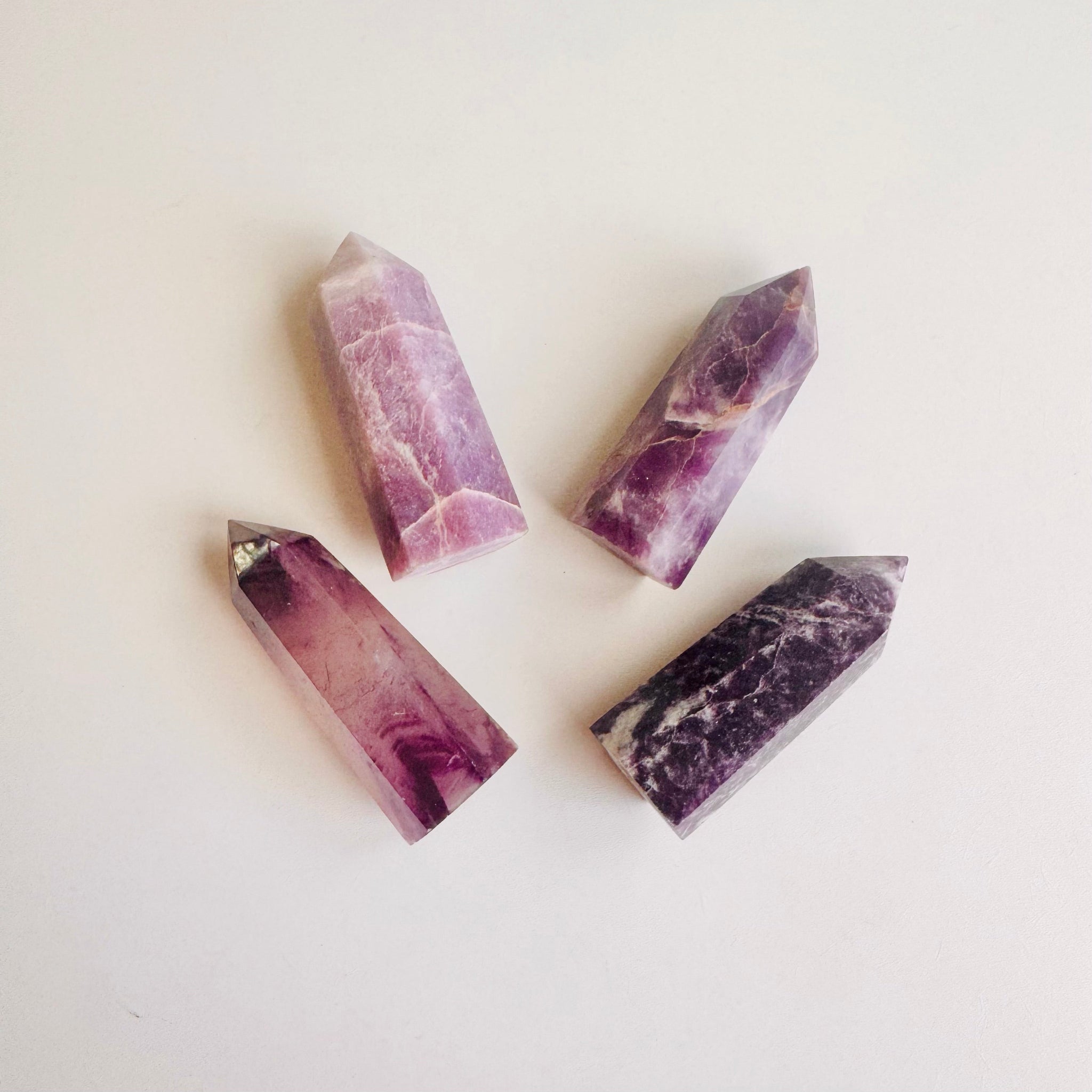 Four Amethyst crystal tower points with varying shades of purple, ideal for meditation and spiritual clarity.