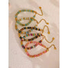 Set of colorful beaded bracelets with gold accents on a textured surface