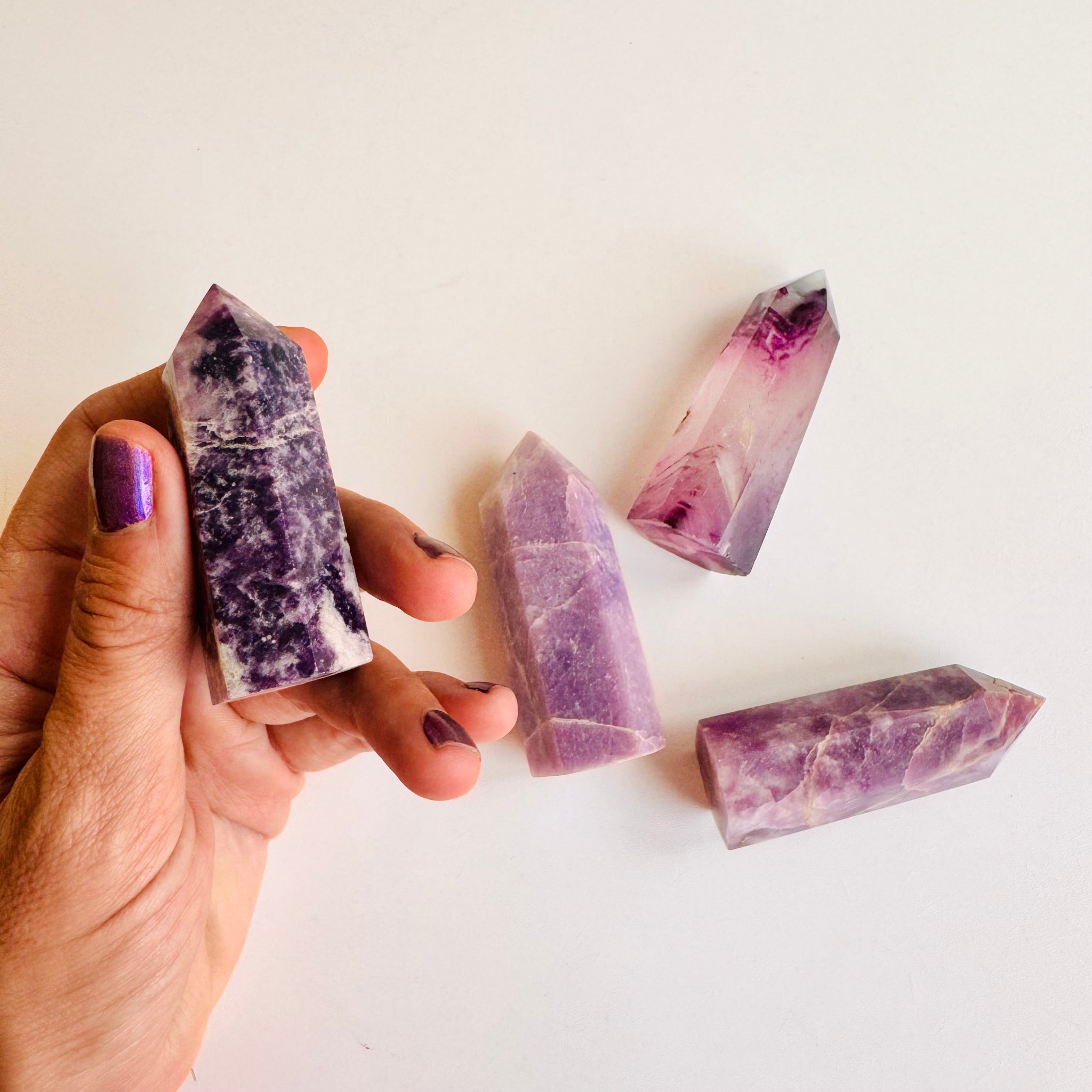 Hand holding a dark purple Amethyst tower point, demonstrating the size and crystal structure, used for Third Eye awakening.