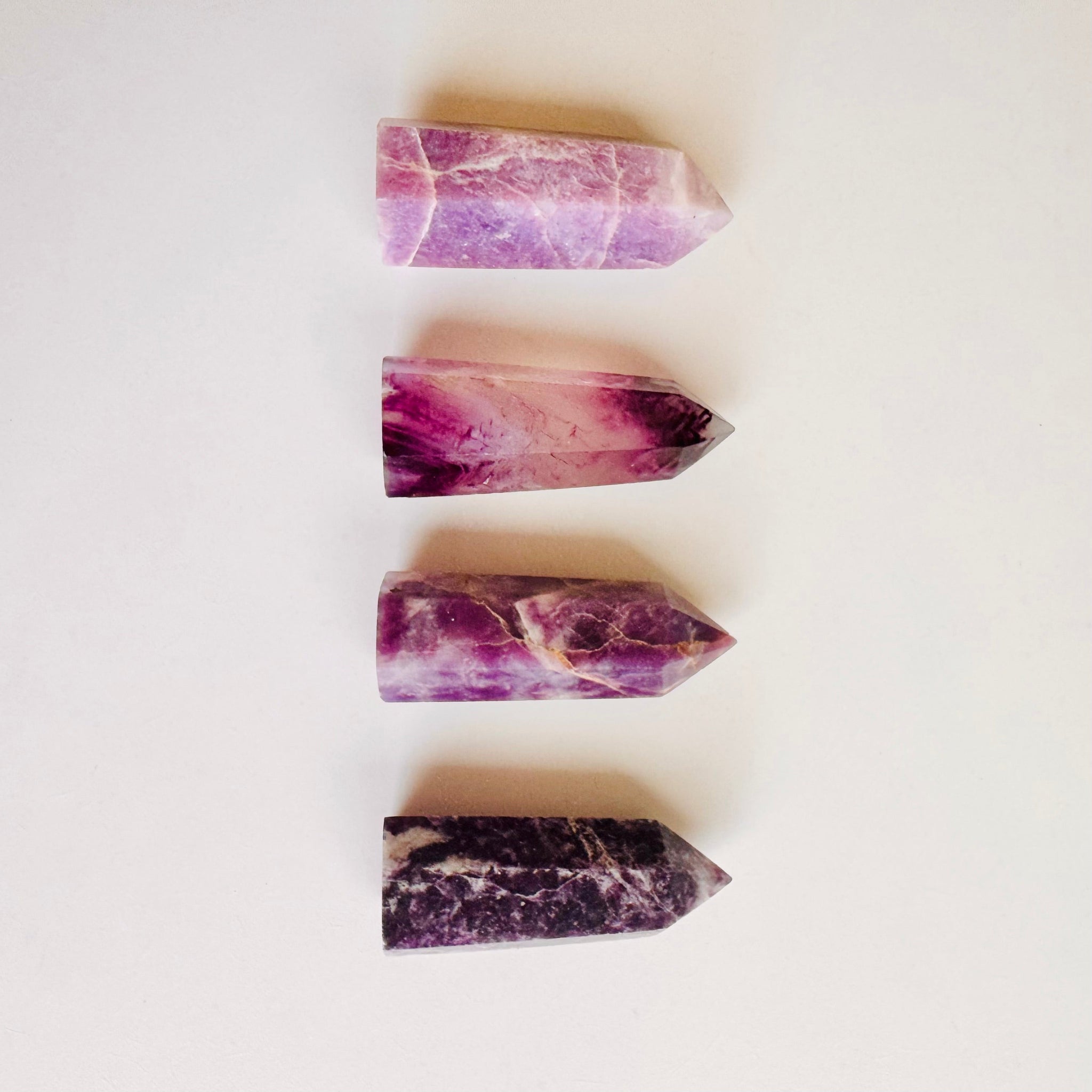 Close-up of four raw-cut Amethyst points showcasing lilac, deep purple, and chevron patterns for crystal healing.