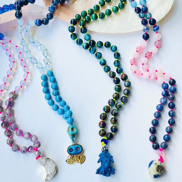 Colorful beaded necklaces on white background with different pendants