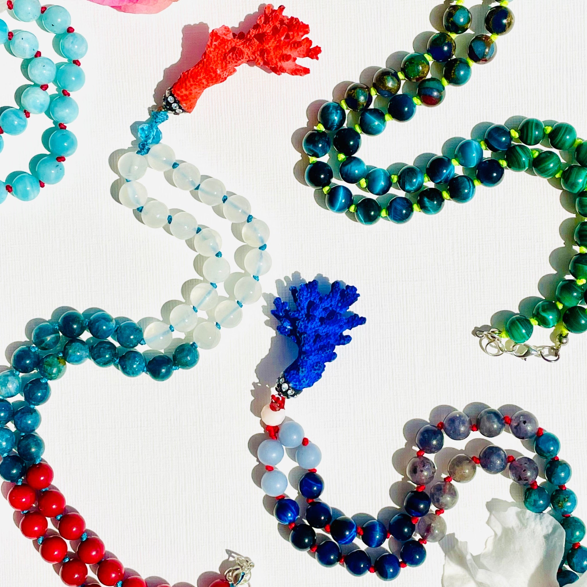 Colorful assorted half mala necklaces on white surface