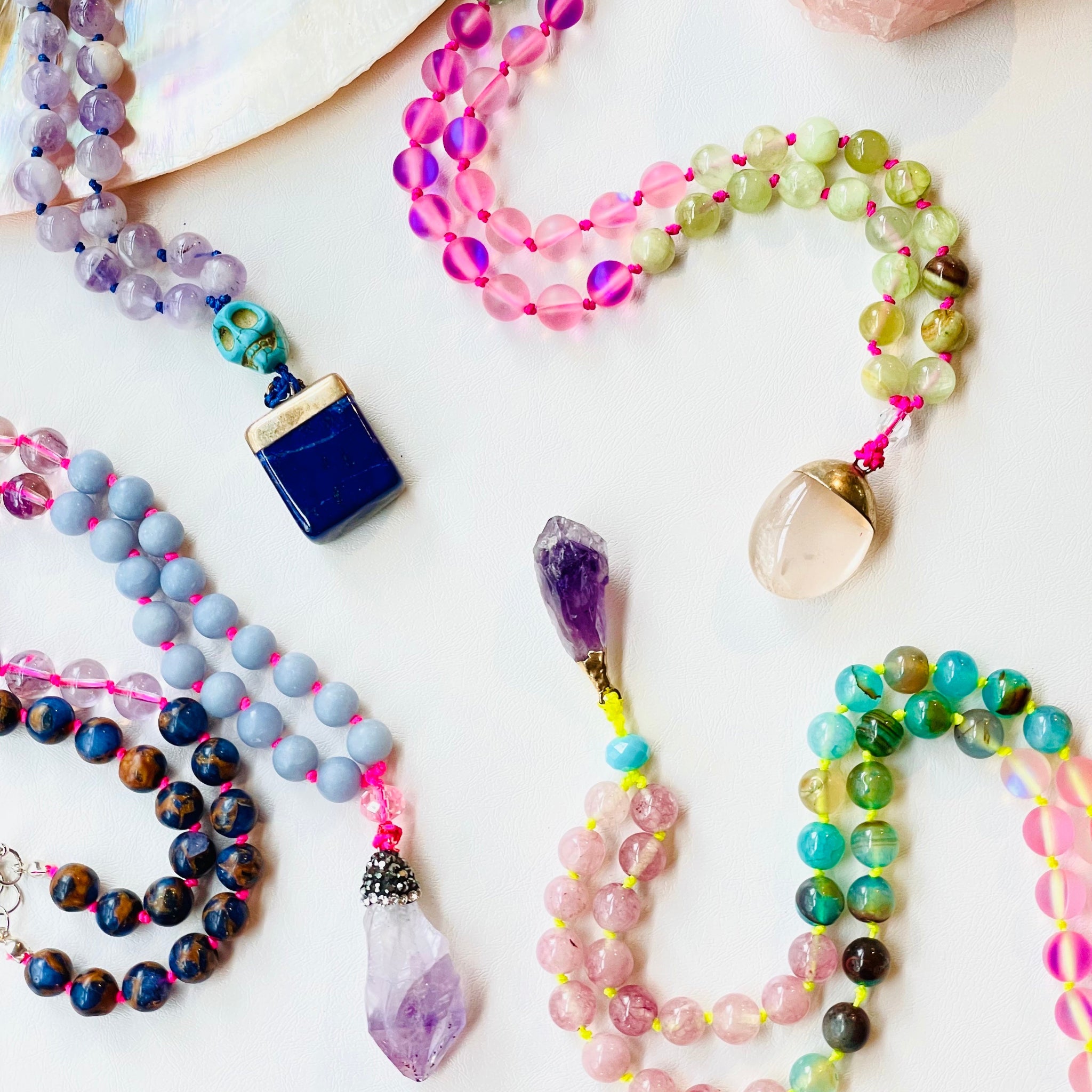 Colorful beaded necklaces with various stones on a white surface