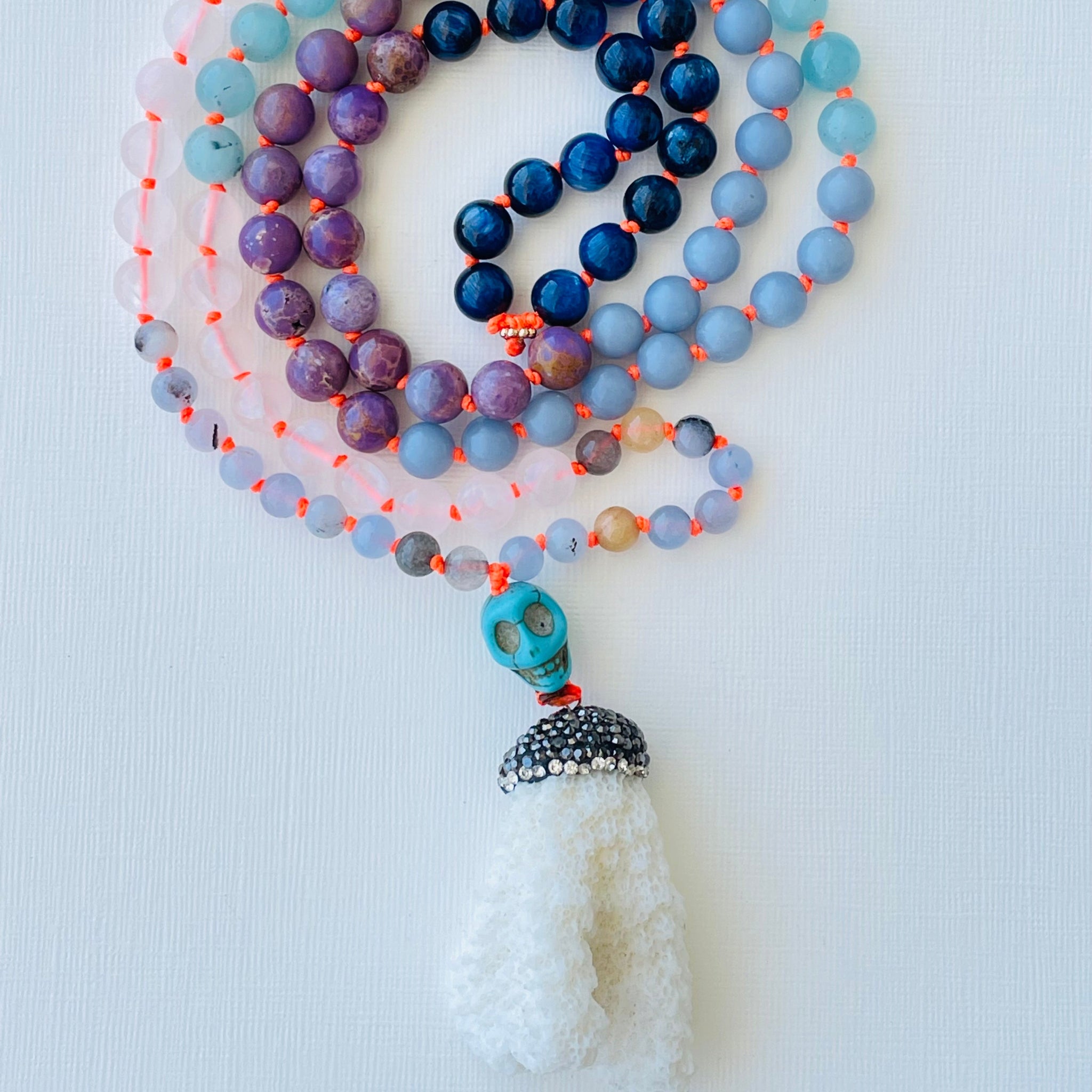 A multicolored beaded mala in spiral with blue purple and clear gemstones