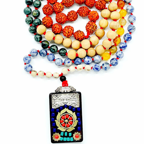 A multicolored beaded mala with a Ganesha bead accent, featuring a red knot and a metal pendant with a Ganesha image.