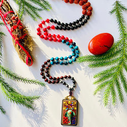 blue red and black gemstones beaded with elephant wood carved pendant on white surface with pine needles