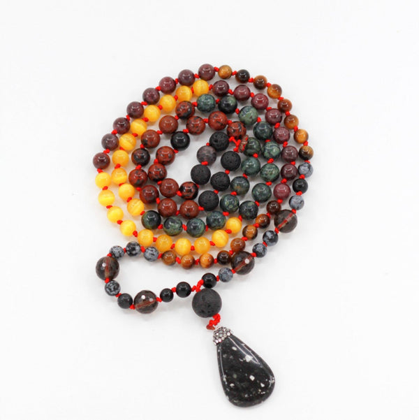 Beaded gemstone mala with black brown yellow beads on white surface